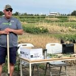 Ken Coles, executive director of Farming Smarter, stands beside a table leaning on a shovel and talking about cover crop benefits at a recent field school.