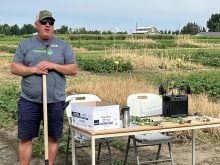 Ken Coles, executive director of Farming Smarter, stands beside a table leaning on a shovel and talking about cover crop benefits at a recent field school.