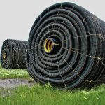 Spools of black PVC tile drainage pipe on a Manitoba field. Photo: File