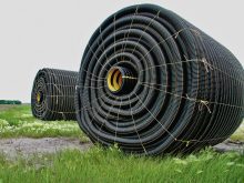 Spools of black PVC tile drainage pipe on a Manitoba field.  Photo: File
