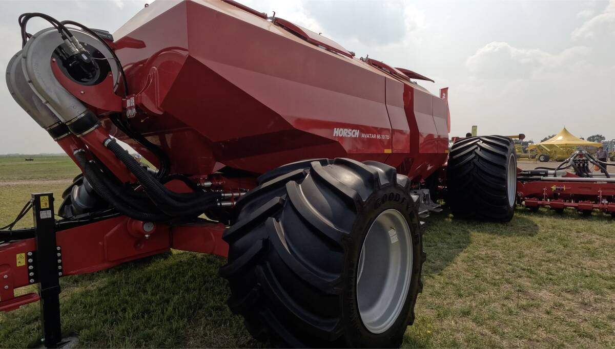 A large, red Horsch grain cart sits on display at the Ag in Motion farm show connected to Horsch's new seed drill.