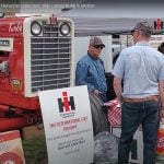 Two men in ball caps chat in front of a vintage International 1206 tractor on display at the Western Canada International Harvester Club, chapter 38, booth at the Ag in Motion farm show near Langham, Sask., in July of 2025.