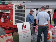 Two men in ball caps chat in front of a vintage International 1206 tractor on display at the Western Canada International Harvester Club, chapter 38, booth at the Ag in Motion farm show near Langham, Sask., in July of 2025.