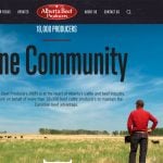 A screencap from th Alberta Beef Producers homepage showing two livestock producers in ball caps looking out over a pasture with cattle on it with the words, "One Community" overtop the image.