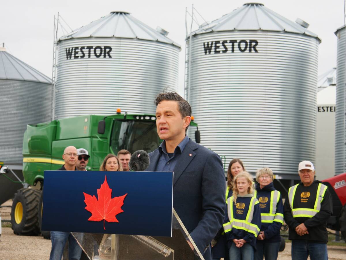 Pierre Poilievre speaks to the crowd at Sixteen Grains farm near Saskatoon, Sask., with some steel grain bins in the background.
