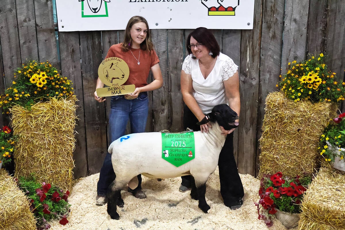 Two women pose with the "Supreme Champion Ram" at a sheep show.