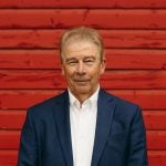 Dennis Laycraft, Executive Vice President of the Canadian Cattle Association is pictured standing against a vivid red barn in the background.