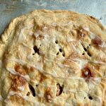 An apple pastry seen from above, fresh out of the oven and still on a metal baking sheet.