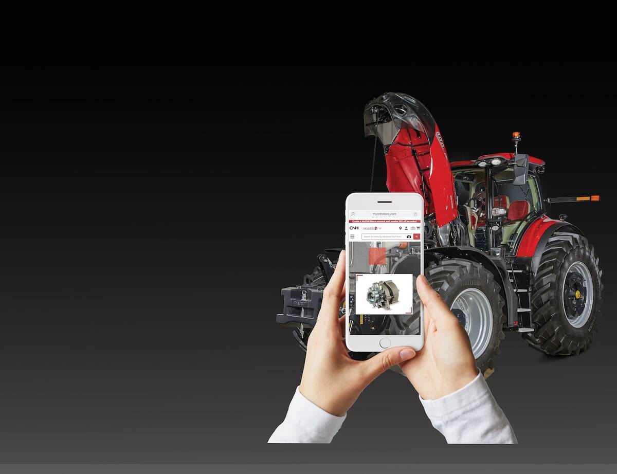 Two hands hold a smart phone in front of a tractor with its hood up, the phone appears to have zoomed in on a specific part and a photo of that part is visible on a CNH website.