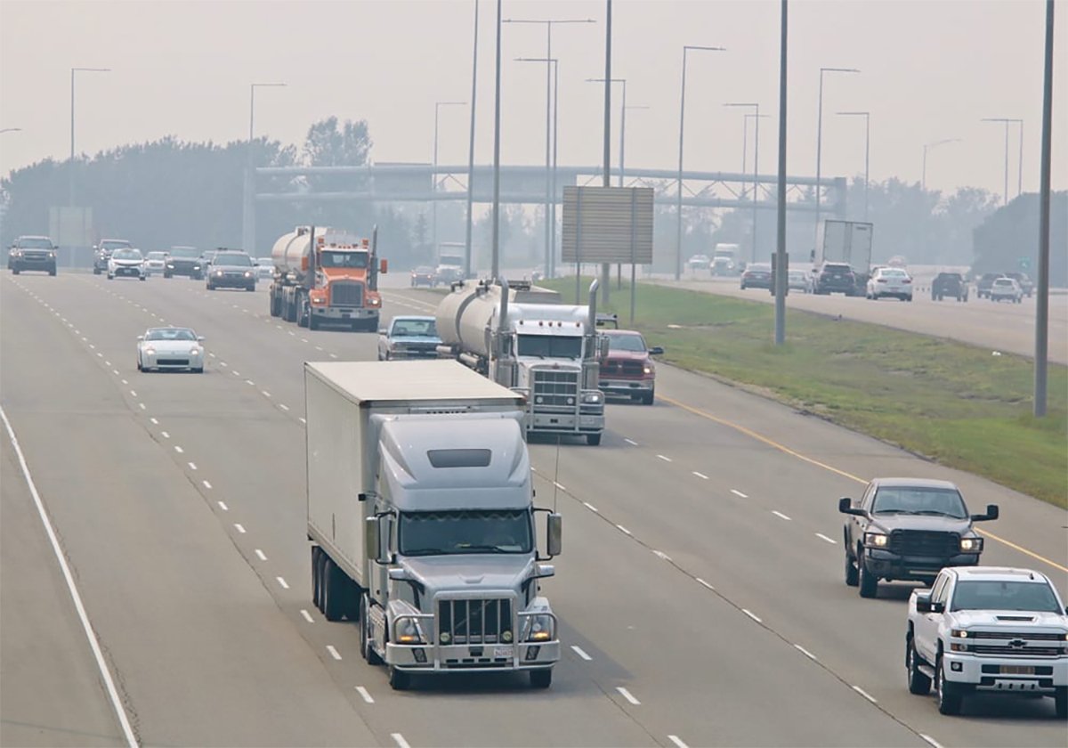 Traffic on a busy urban highway on a hazy day with several large transport trucks in the centre of the image.