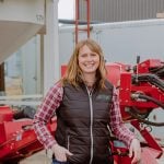 Alberta Outstanding Young Farmer Sarah Weigum poses beside a piece of farm equipment.