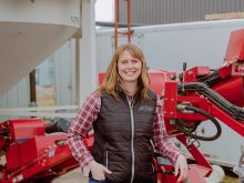 Alberta Outstanding Young Farmer Sarah Weigum poses beside a piece of farm equipment.