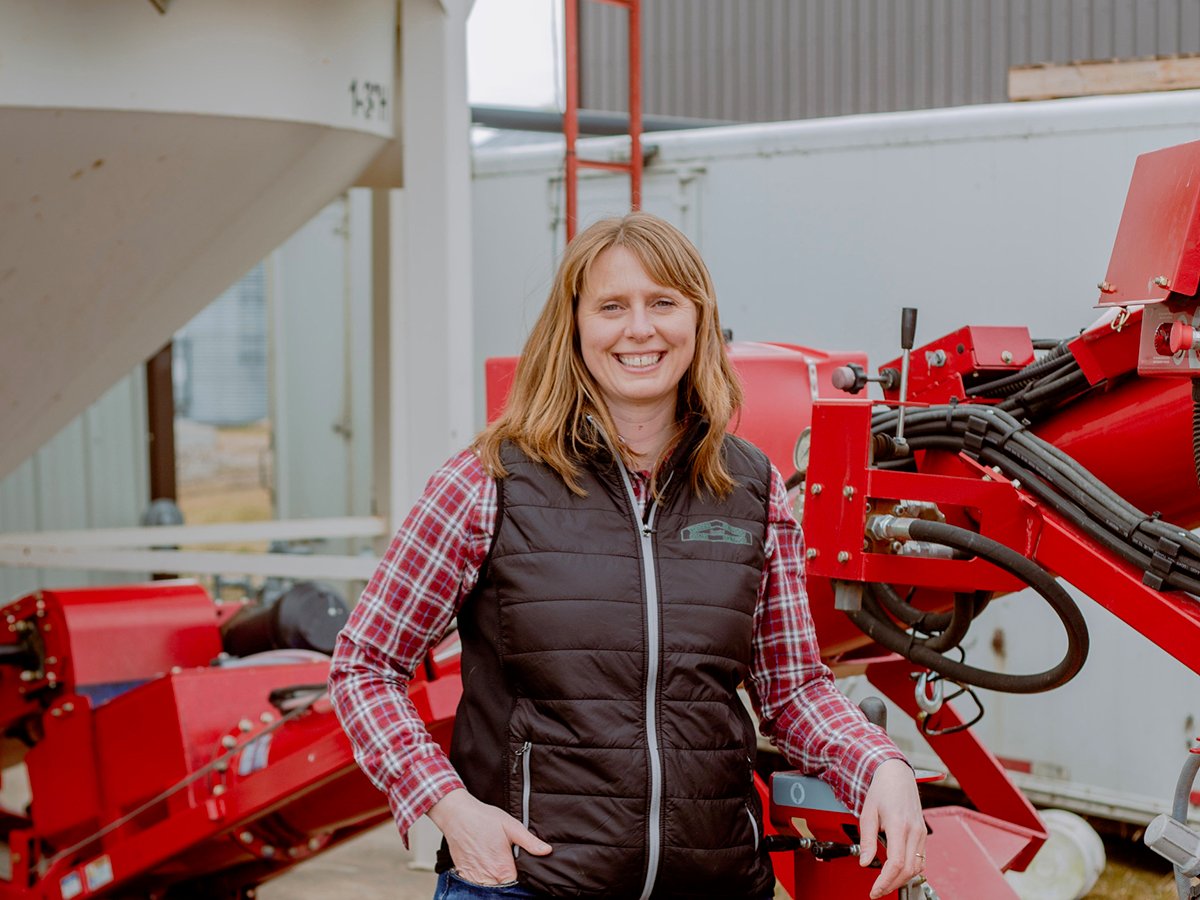 Alberta Outstanding Young Farmer Sarah Weigum poses beside a piece of farm equipment.