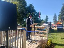 A man in a black cowboy hat speaks from a lectern at Canada's Outdoor Farm Show in Ontario.