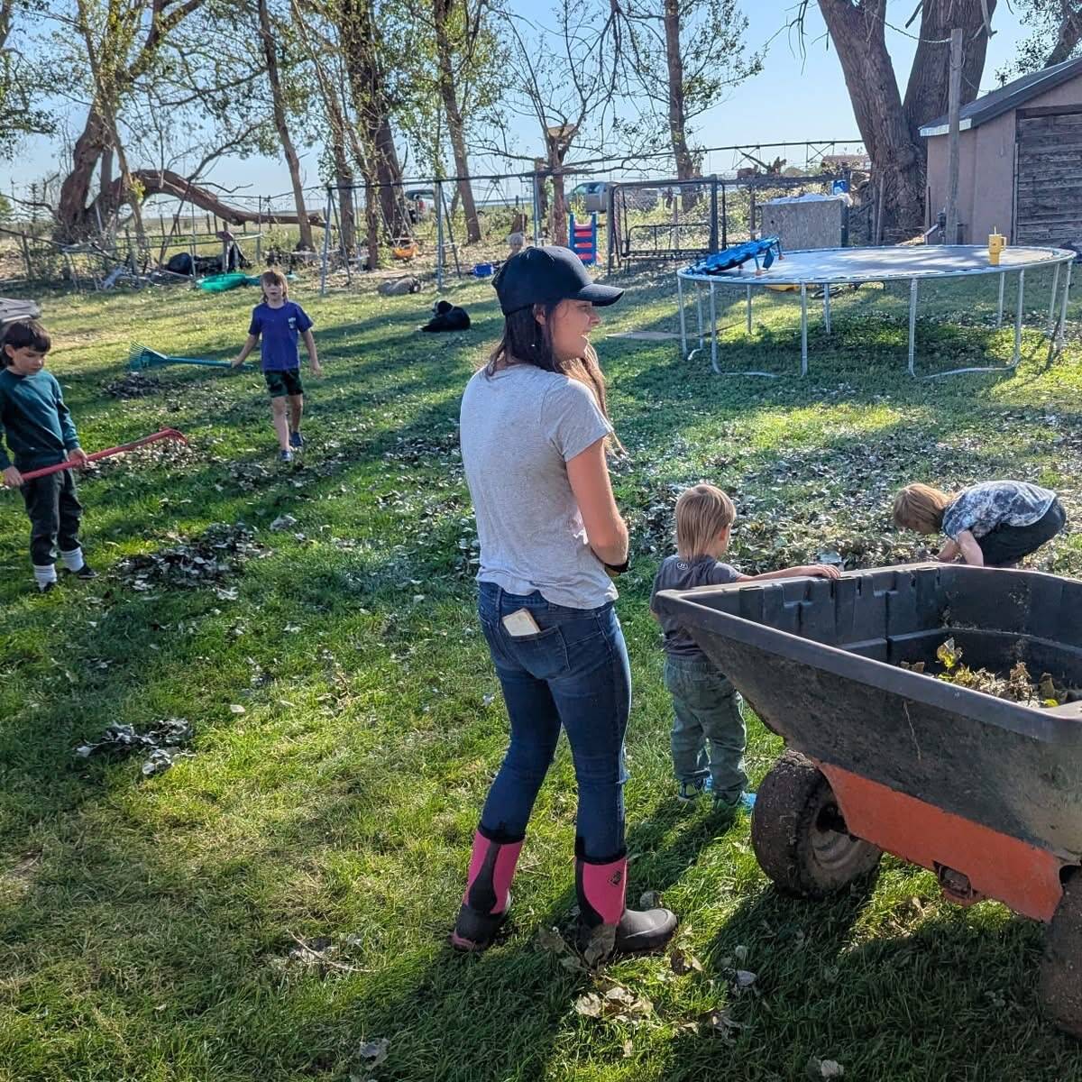 A woman and four small children work to clean up leaves at the White Barn Fun Farm.