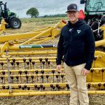 Bart Elder, of Vermeer, stands in front of the company's yellow basket rake.