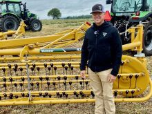 Bart Elder, of Vermeer, stands in front of the company's yellow basket rake.