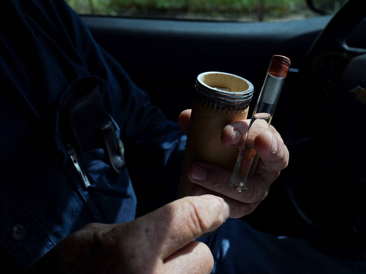 A man holds one of the canisters ranchers would use to ship a test tube with samples to determine if they were dealing with screwworms in the 1970s.