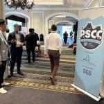 Delegates mingle in the doorway of a large meeting room with a large "PSCC logo" and sign on the door at the annual Pulse & Special Crops Convention in Whistler, B.C., in September 2025.
