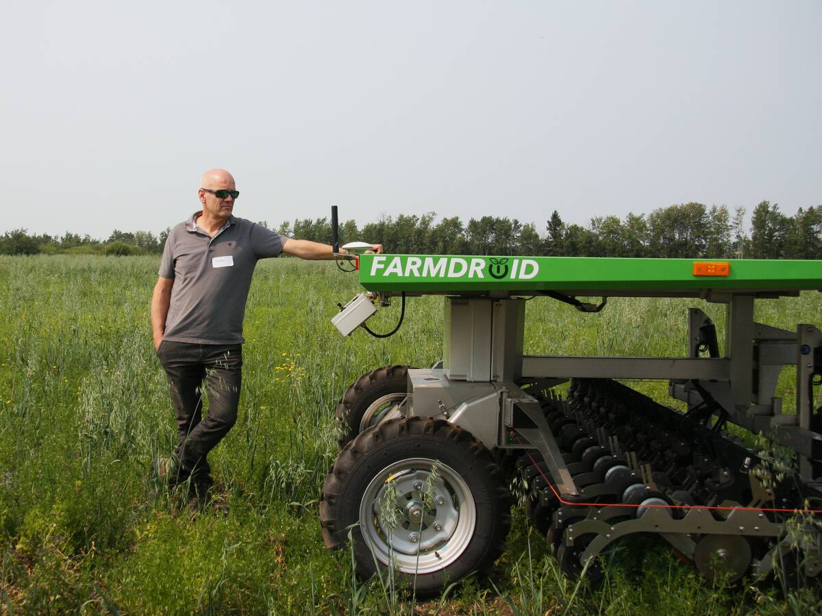 Stefan Graner stands with his left hand on his robotic FarmDroid seeder and weeder at his farm near Paddockwood, Saskatchewan.