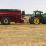 A photo of an autonomous tractor pulling a grain cart in a field.