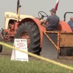 An antique tractor' front end rises into the air as its driver takes part part in a tractor pull while fans look on at the Ag in Motion Farm show near Langham, Saskatchewan, during the July 2025 show.