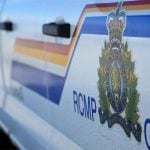 A close-up of the door of a white police vehicle featuring the logo and blue, red and yellow striping of the Royal Canadian Mounted Police.