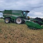A combine is parked in a field under a cloudy sky.