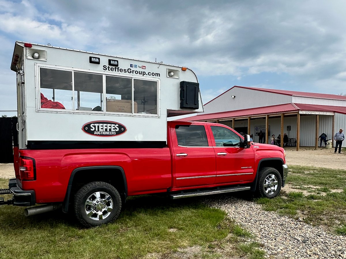 A red half-ton truck with a modified camper in the box and