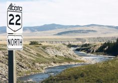 A road sign for Alberta's "Highway 22 North" stands overlooking a river in the background near the province's Waldron Ranch.