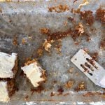 Three pieces of carrot cake and a spatula are all that remain in a large cake pan.