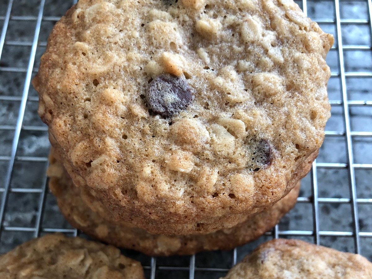 Close-up of the top of a stack of two chocolate chip cookies sitting on top of stainless steel grate to keep the cookies off the bottom of a baking sheet.