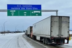 A line of semi trailers wait on a highway to cross the Canada/U.S. border at Emerson, Manitoba.