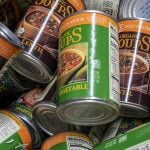 A variety of Annie's Organic Soups cans sit on top of one another in some kind of container.