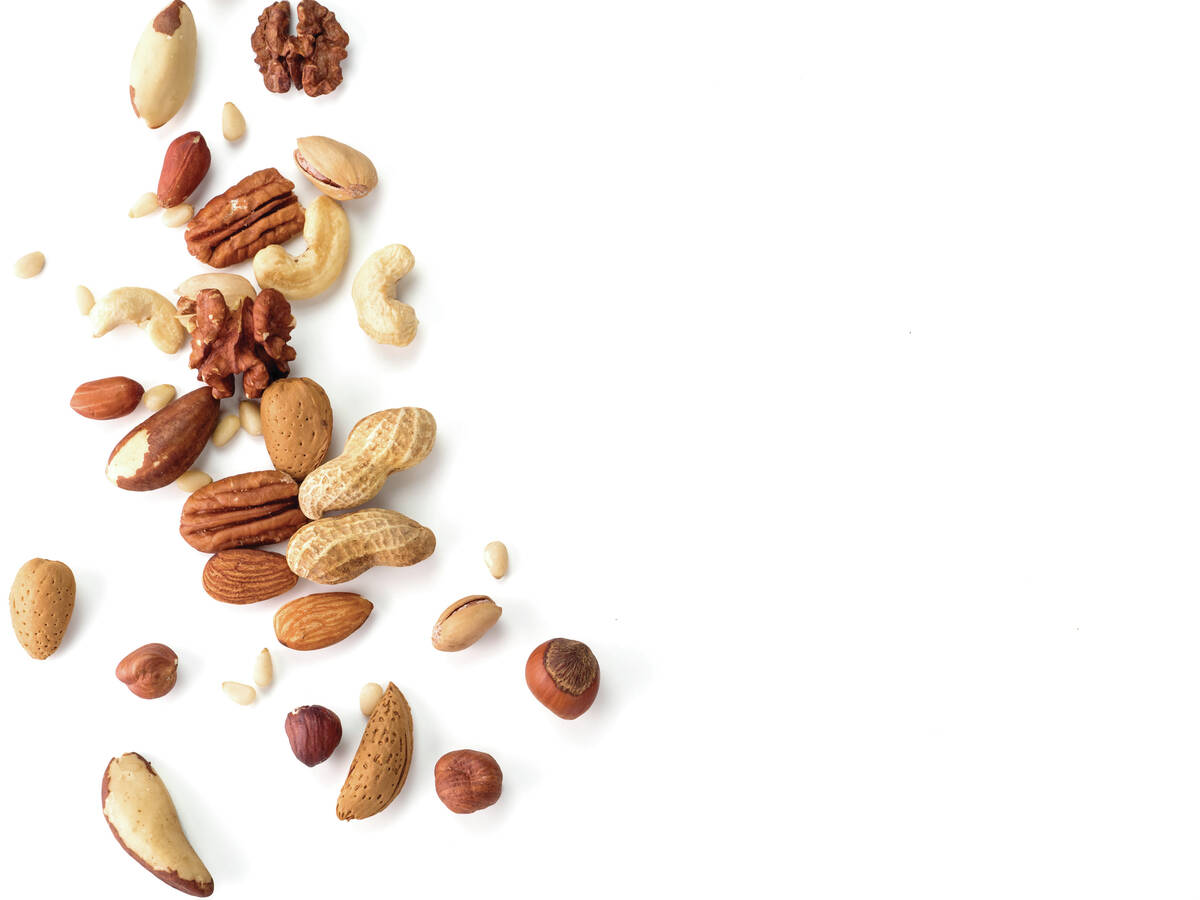 Background of nuts - pecan, macadamia, walnut, almonds, hazelnuts, and other - with copy space. Isolated one edge. Top view or flat lay