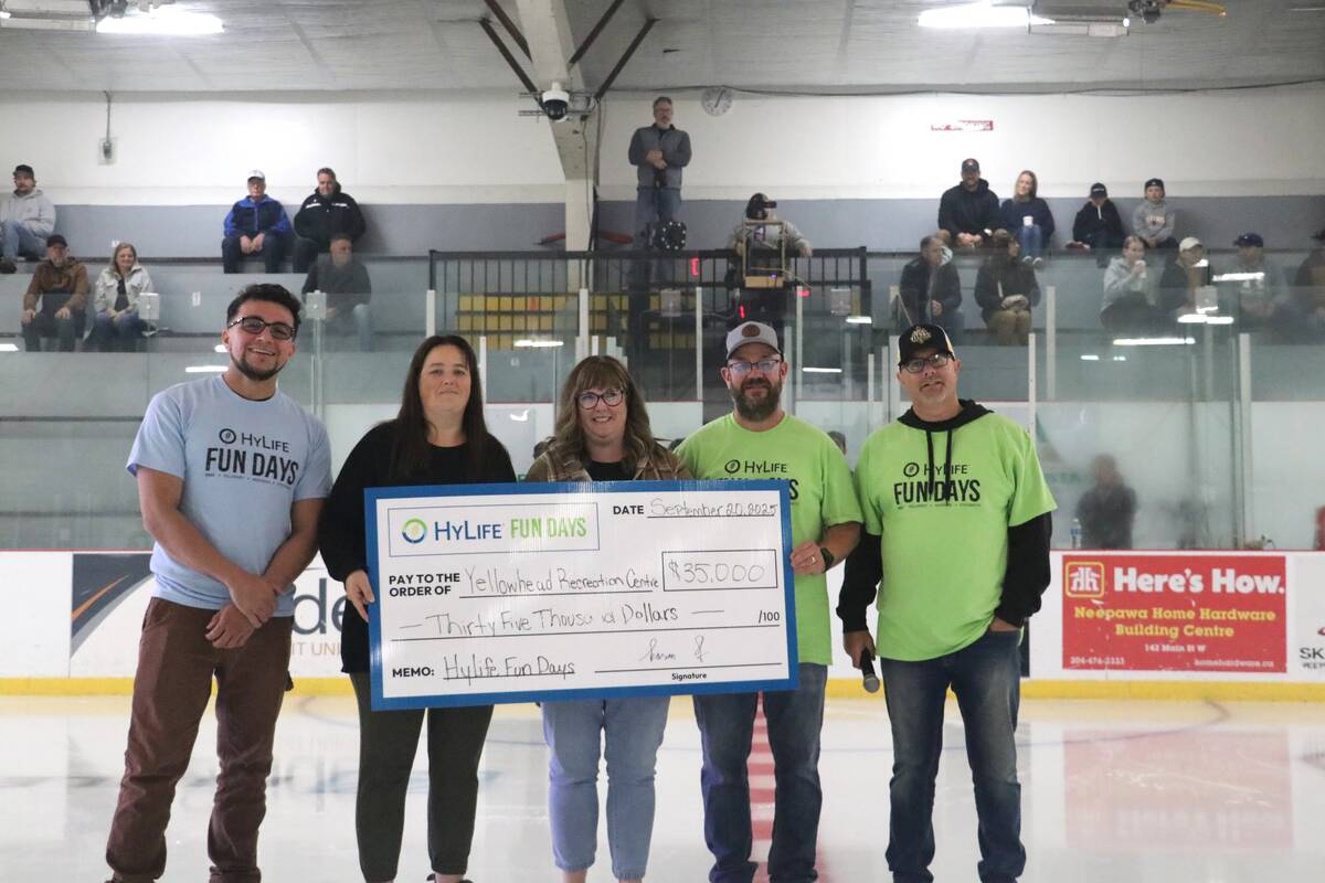 Five people stand at centre ice in a hockey arena holding a large cheque for $35,000 from