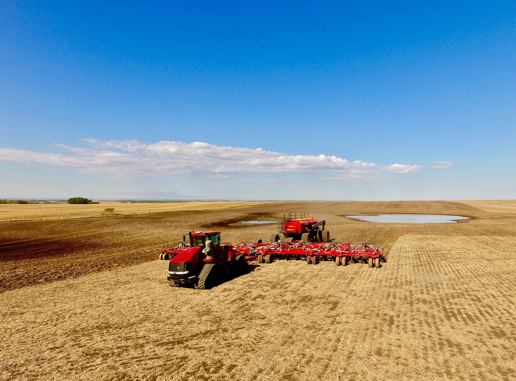 A tractor in a field, using a plow to turn the soil in preparation for seeding crops.
