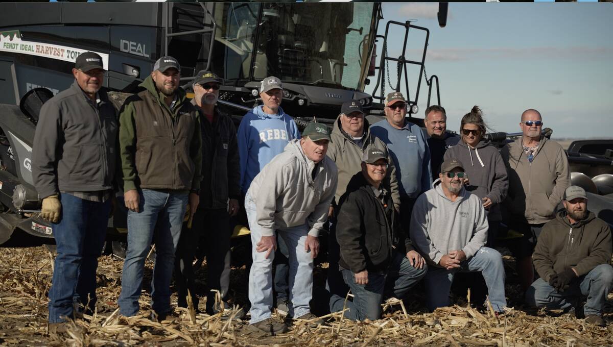 A group of farmers pose for a photo in front of a Fendt Ideal combine taking part in a Harvest Tour to show off the machine's capabilities.
