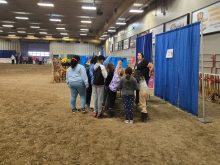 Students stand in a group in front of a display booth at a farm show.