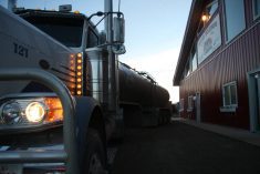 The sun is rising in the background as a semi truck hauling milk is parked outside a facility near Picture Butte, Alberta.