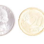 An American and Euro 20 cent coin are shown with the 8 mm by 8 mm size of the Iridium PNT ASIC chip.
