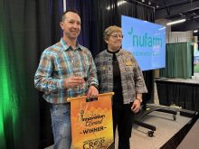 Travis Albrecht of WEED-IT Canada stands on stage at the Western Canadian Crop Production Show holding his Innovation Award for 2026 alongside Prairieland Park Agriculture Manager Leigh Ann Hurlburt.