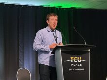 A man stands at a podium on stage speaking during the Saskatchewan Seed Growers annual general meeting, held in conjunction with the Western Canadian Crop Production Show in Saskatoon.