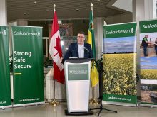 Saskatchewan Premier Scott Moe stands at a podium speaking to media following his return from China.