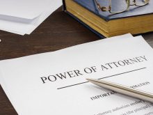 A pen sits on a document entitled, "Power of Attorney" on top of a desk.