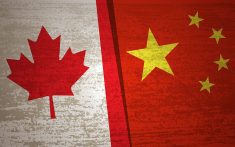 The flags of Canada and China overlap one another.