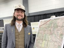 Alex McPhee of Pronghorn Maps poses beside one of his maps on display at Canadian Western Agribition in Regina in 2025.