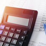 Calculator with pen on white paper with numbers.