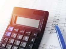 Calculator with pen on white paper with numbers.