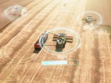 An aerial view of several combines and a grain truck at work in a wheat field with data superimposed over each combine indicating how much crop it has onboard.